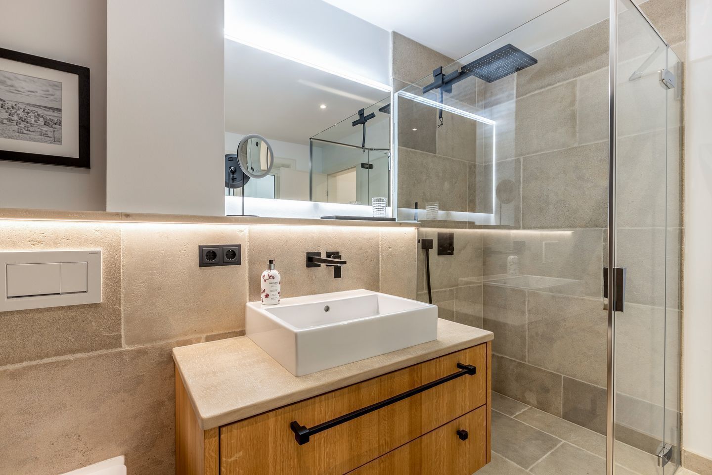 Een moderne badkamer met een rechthoekig wastafelmeubel, een spiegel erboven en een douchecabine met glazen wanden.