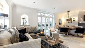 Ein geräumiges Wohnzimmer mit einer großen Couch, einem Couchtisch und einem Essbereich mit Tisch für vier Personen.