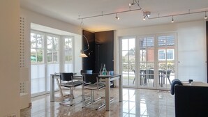 Un vaste espace de vie comprenant une table à manger, des chaises, un canapé et une grande fenêtre offrant une vue sur l’extérieur.