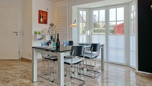 Un espace repas moderne avec une table en verre, des chaises en métal et une vue dégagée grâce à de grandes fenêtres.