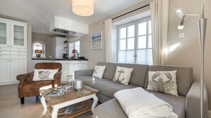 A modern living room with a sofa, armchair, and coffee table. - Sylt-hues - Lifestyle Unter Reet, Strand & Meer um die Ecke. Ihr Optimales Urlaubs-domizil (Wenningstedt-Braderup (Sylt))