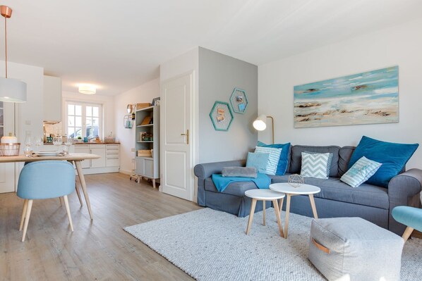 A modern living room with a grey sofa, blue cushions, and a small white table.