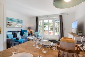 A modern living room with a sofa, dining table, and a painting.