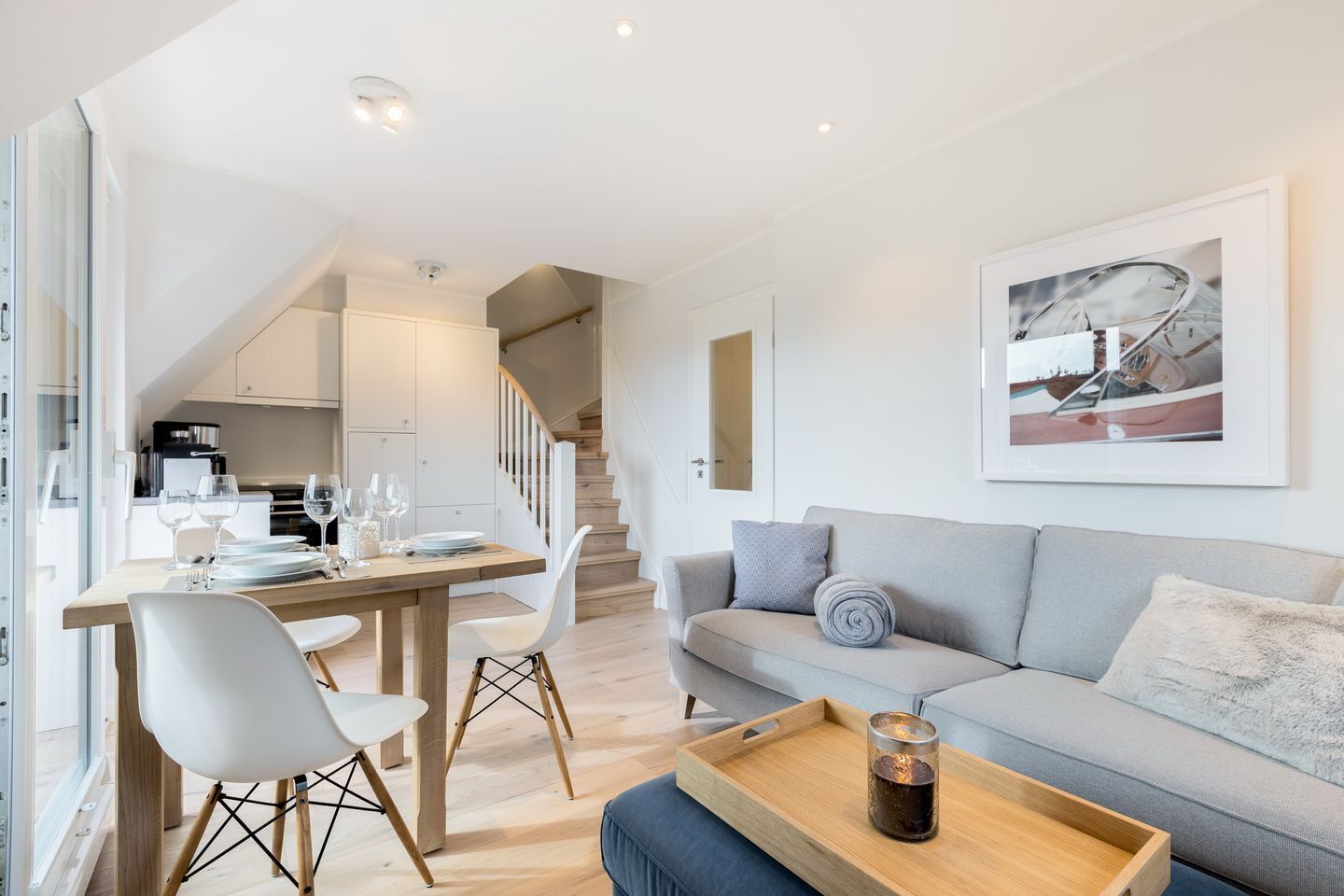 A modern living space with a dining area, a sofa, and a staircase.