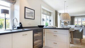 A modern kitchen with a large island, built-in oven, and a dining area with a sofa and table.