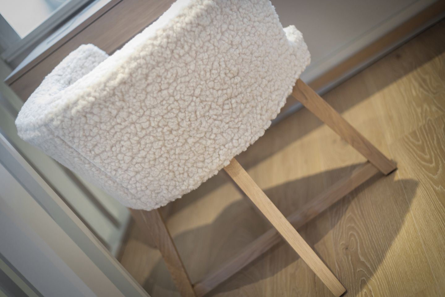 A white, textured chair with a round backrest on a wooden floor.