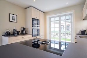 Una cocina moderna con una isla central, electrodomésticos integrados y vistas al exterior.