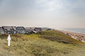 A coastal residential area with modern houses, a beach, and a grassy hill. - Schloss am Meer, App. 27 - Strandnäher Können Sie in Wenningstedt Kaum Urlauben (Wenningstedt-Braderup (Sylt))