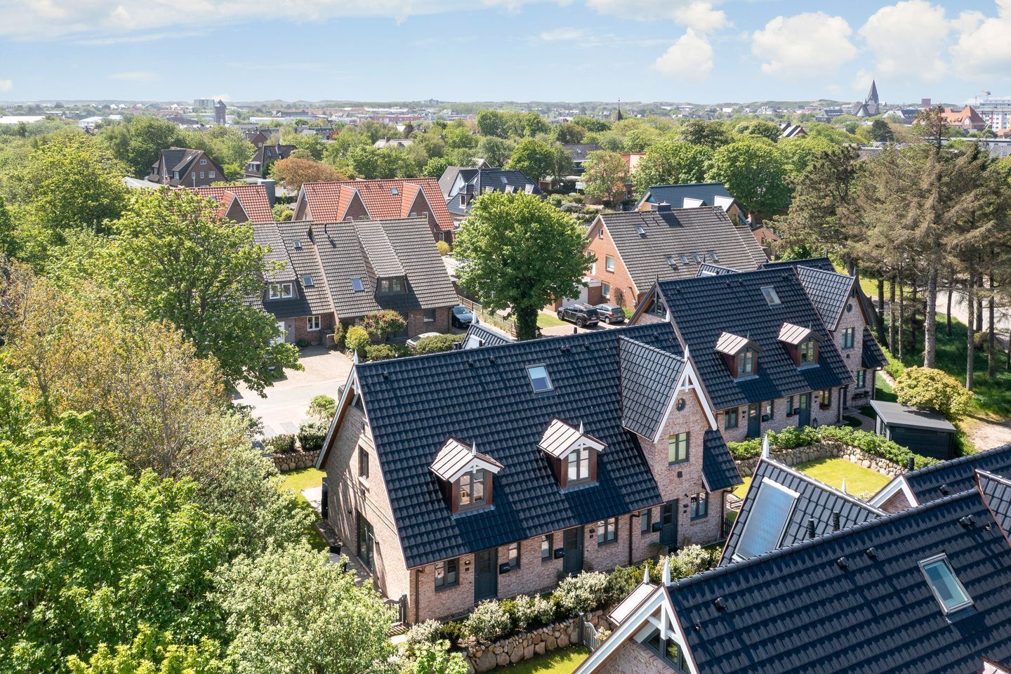 A residential area with multiple houses featuring steeply pitched roofs and brick construction.