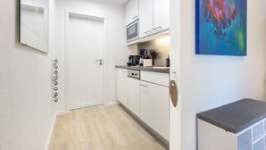 A modern kitchen with white cabinets, a microwave, and a coffee maker on the countertop. - Badezeit - Verbringen Sie Ruhige Tage in Modernem, Designorientiertem Ambiente (Wenningstedt-Braderup (Sylt))