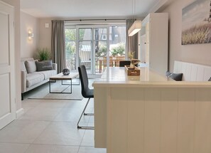 Uma sala de estar moderna com sofá, mesa de centro e área de jantar com cadeiras.