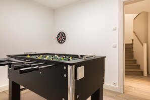 Ein Kicker steht in einem Raum, an der Wand ist eine Dartscheibe angebracht.