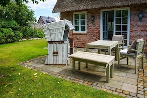 A patio with wicker furniture, a table, and a bench.