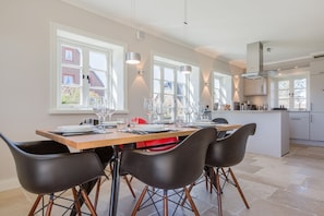A modern kitchen with a dining area, large windows, and a central island.