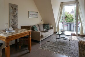 En hyggelig stue med en sofa, et træbord, et glasbord og udsigt udad.