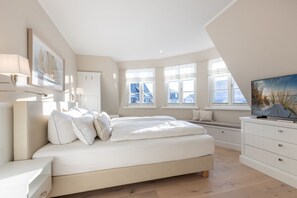 Una camera da letto moderna con un letto grande, una TV e vista sulla città attraverso ampie finestre.