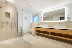 A modern bathroom with a glass-enclosed shower, a large mirror, and a wooden vanity.