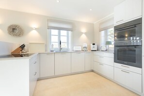 Una cucina moderna con mobili bianchi, forno integrato e una finestra che offre luce naturale.