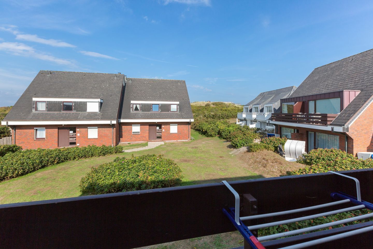 Een woonwijk met twee verdiepingen tellende huizen, een gazon en een heldere lucht.