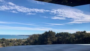 Una vista panoramica di un paesaggio costiero, con cielo sereno, vegetazione lussureggiante e una costa in lontananza.