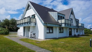 A modern two-story house with a balcony, a bicycle, and a well-maintained lawn. - Wallhof, App. 6 - Urlauben und Relaxen im Haus Wallhof - Genießen Sie Sylt in Vollen Zügen (Wenningstedt-Braderup (Sylt))