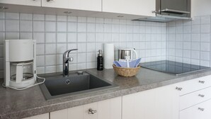 A modern kitchen with a built-in sink, a coffee maker, and a basket with utensils.