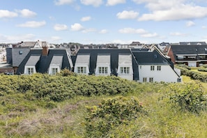 A row of houses with steeply pitched roofs, surrounded by dense shrubbery.