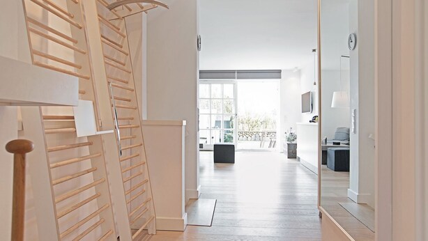 Un interior moderno con una escalera de madera, un ventanal grande y una zona de estar minimalista.