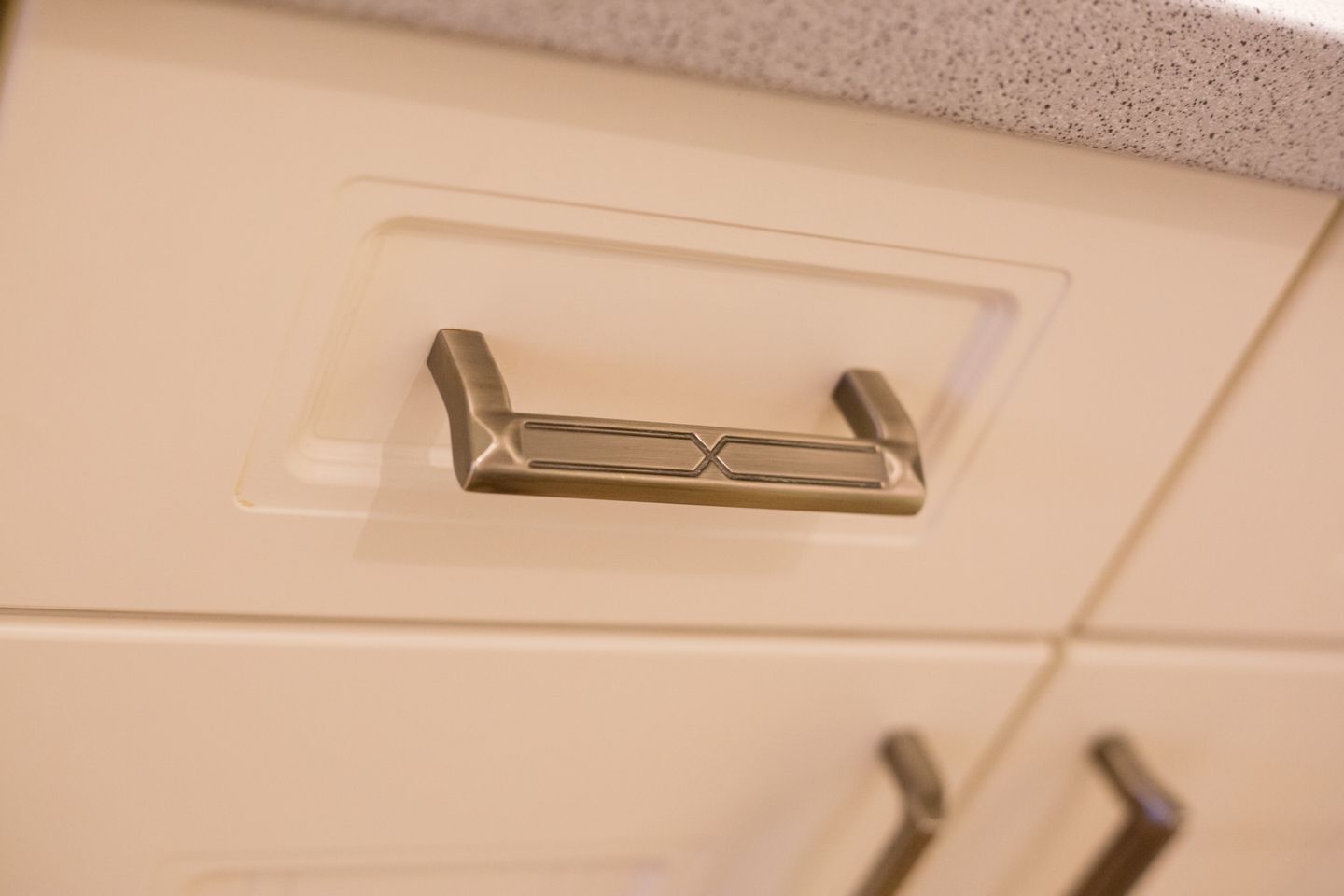 A kitchen cabinet with a metallic handle and a frosted glass window.