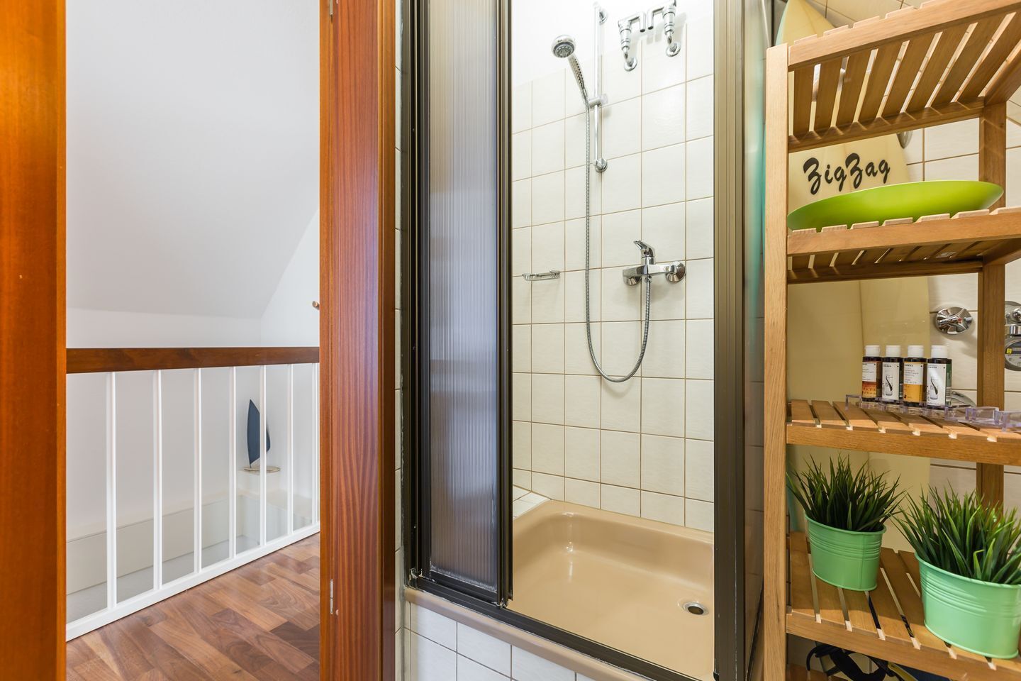 Un baño con ducha, bañera y un estante con artículos de aseo.
