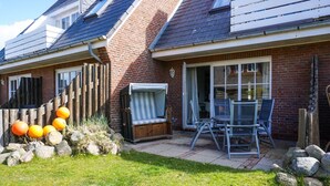 Il s’agit d’une propriété résidentielle avec une façade en briques, un patio aménagé avec du mobilier d’extérieur et une clôture en bois.