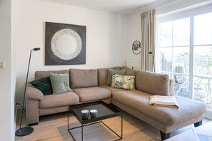 En stue med en beige sofa, et sofabord og en gulvlampe.