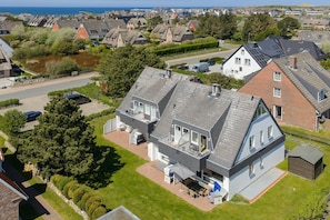 A modern house with a large patio, a garage, and a view of the sea.