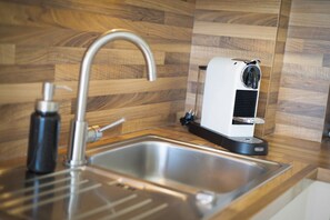 A kitchen with a stainless steel sink, a modern faucet, and a compact electric kettle.