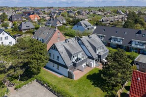 A residential area with modern houses, including a two-story house with a sloped roof and a detached garage.