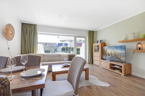 A modern living room with a dining area, a TV, and a view of the outdoors.