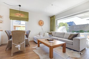 A modern living room with a sofa, chairs, a coffee table, and a large window with a view.