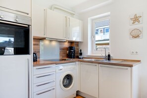 Een moderne keuken met een inbouw wasmachine, een koffiezetapparaat en een raam met uitzicht.