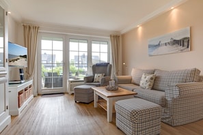 Una sala de estar con un sofá, un sillón y un televisor.