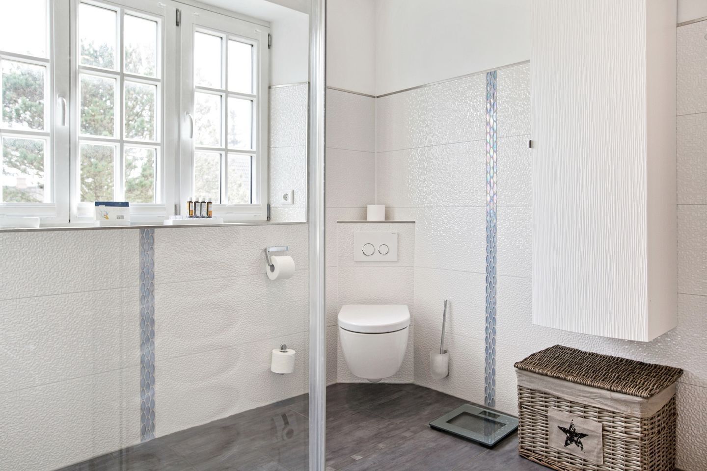 A modern bathroom with a glass shower enclosure, a toilet, and a sink.