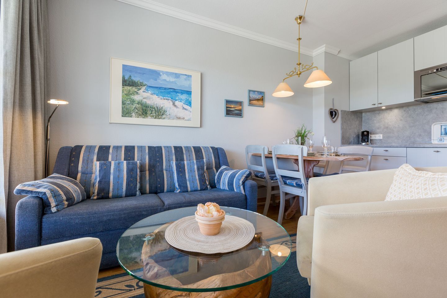Een moderne woonkamer met een bank, een glazen salontafel en een eethoek met stoelen en een tafel.