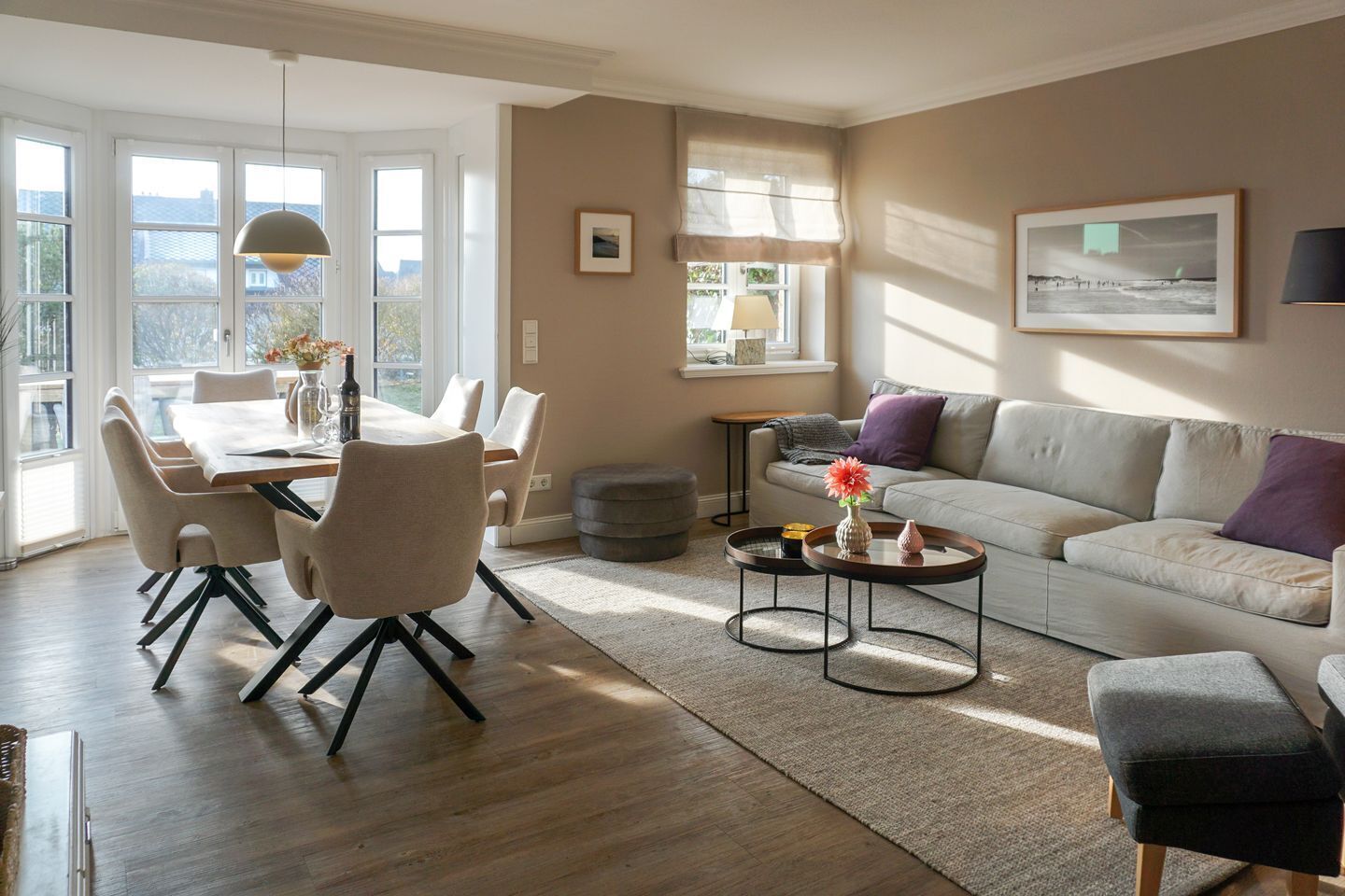 Een moderne woonkamer met een eethoek, met een bank, salontafel en een eettafel met stoelen.