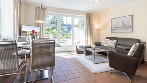 En moderne stue med sofa, sofabord og spiseplads med stole.