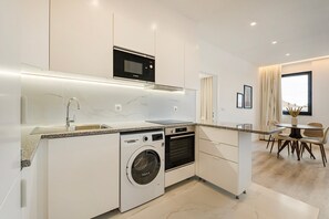 Une cuisine moderne équipée d’un lave-linge intégré, d’un four à micro-ondes et d’un coin repas avec une table et des chaises.