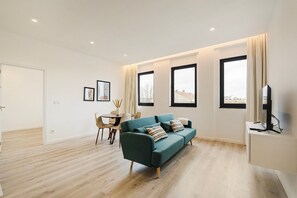 Un salon moderne avec un canapé de couleur turquoise, une table à manger et un téléviseur posé sur un meuble.