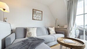 Ein modernes Wohnzimmer mit einem grauen Sofa, einem runden Couchtisch und einer Wandlampe.