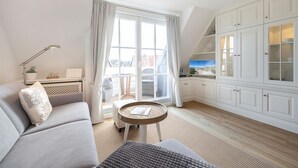 Ein modernes Wohnzimmer mit einer Couch, einem kleinen runden Tisch und Blick auf die Stadt durch große Fenster.