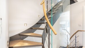 A modern staircase with glass railings and wooden steps.