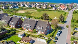 Ein Wohngebiet mit Häusern, einer Straße und Blick auf das Meer.