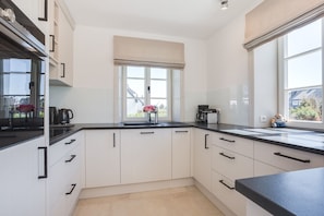 A modern kitchen with white cabinets, black countertops, and a window with a view of the outside.